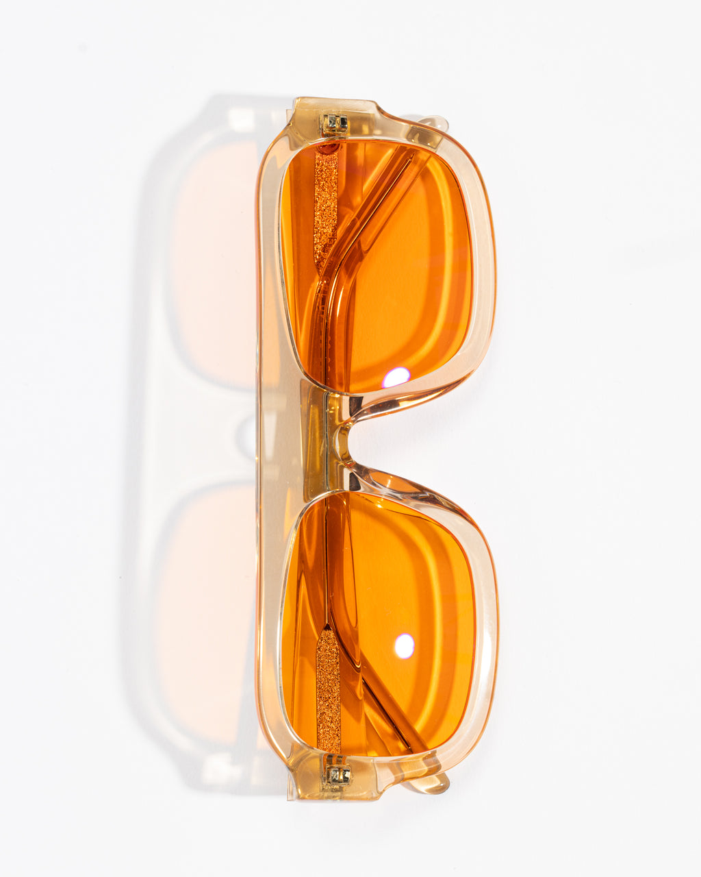 Good In Bed DYLAN blue light blocking glasses in Translucent Honey with amber lenses, vertical product flat lay