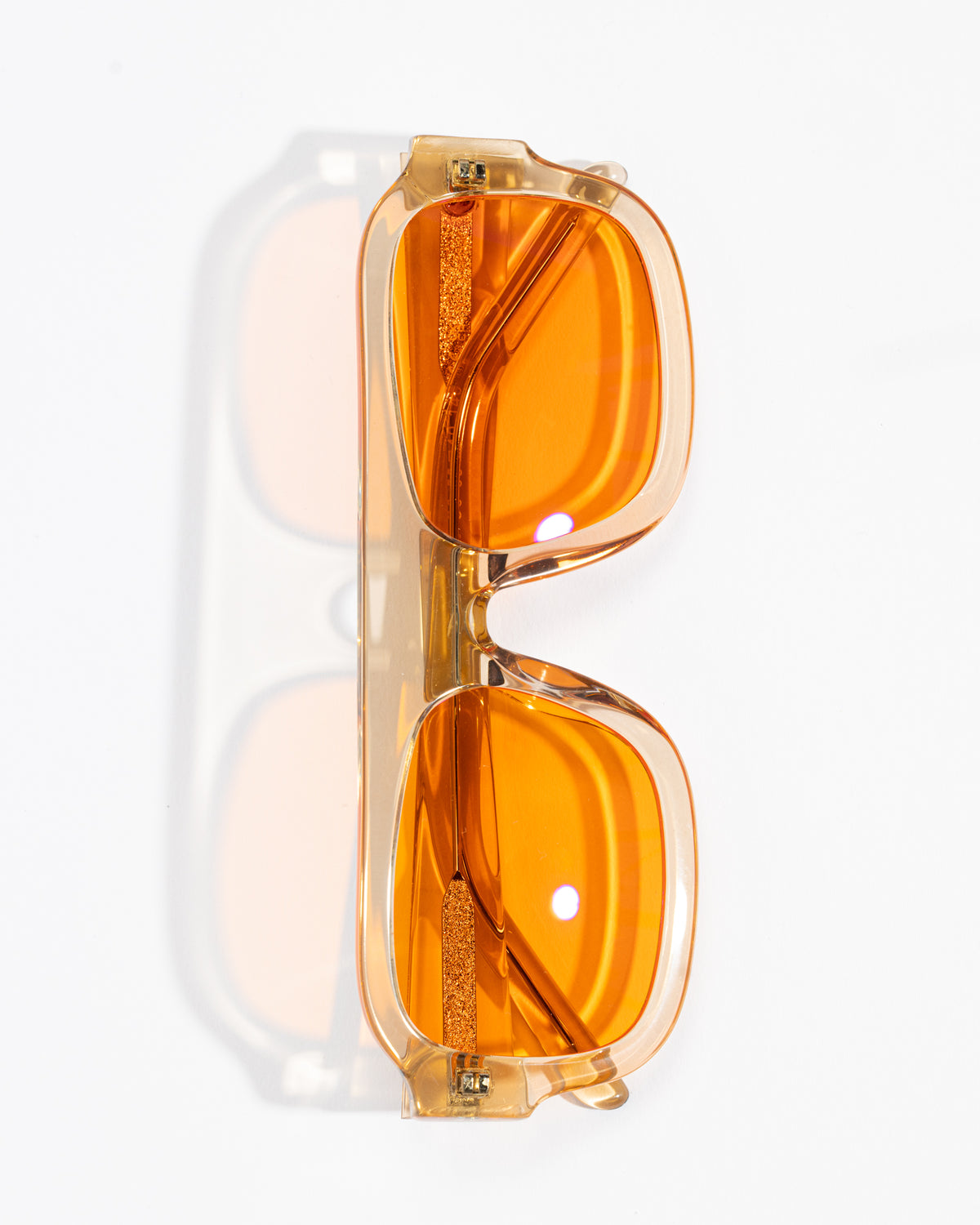 Good In Bed DYLAN blue light blocking glasses in Translucent Honey with amber lenses, vertical product flat lay